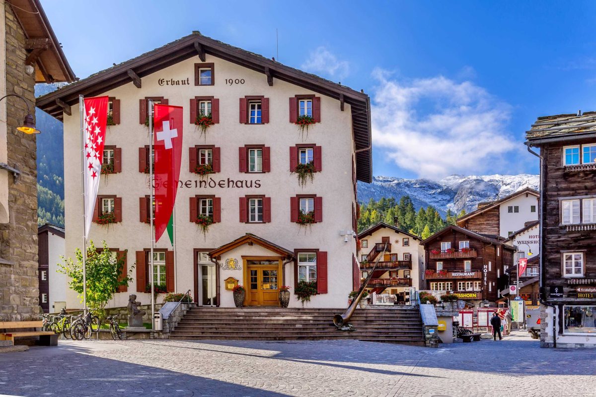 Zermatt, Switzerland - October 7, 2019: Town main street view in famous swiss ski resort, Gemeindehaus, mountains and people
